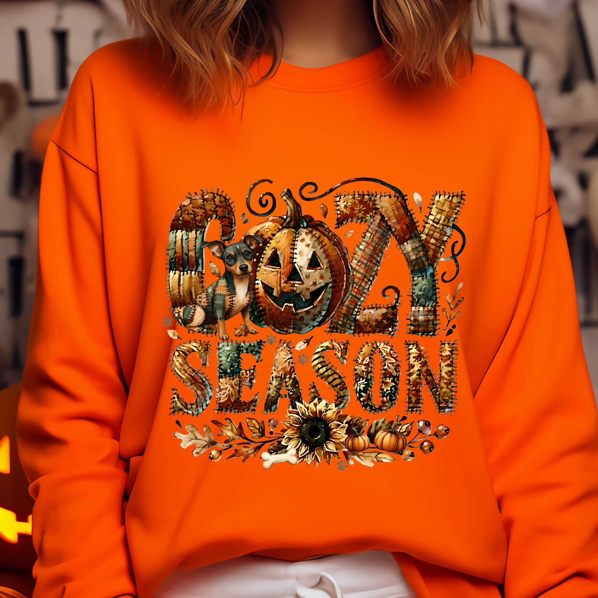 Person wearing an orange sweatshirt with 'GOZY SEASON' design featuring pumpkins and leaves.