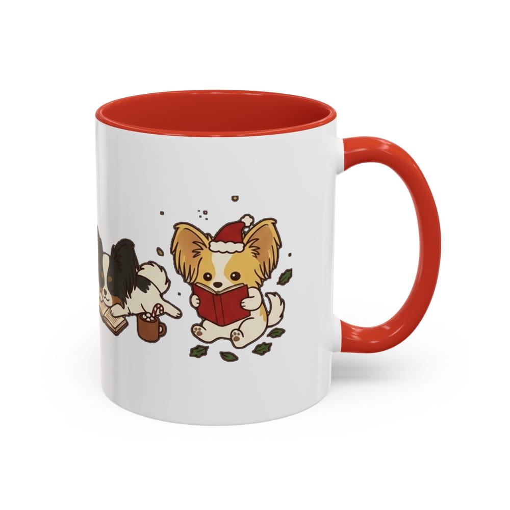 White ceramic mug with a red interior and red handle, showing a Papillon in a Santa hat reading a red book, with another Papillon beside it.