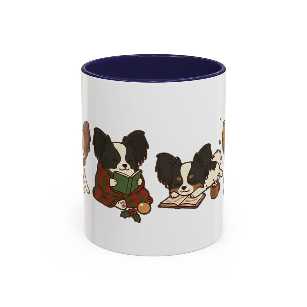 White ceramic mug with a navy interior, showing a Papillon in a plaid blanket reading a green book beside another Papillon lying on an open book.
