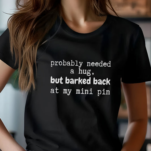 Black unisex t-shirt with white text: "probably needed a hug, but barked back at my mini pin" centered on the chest