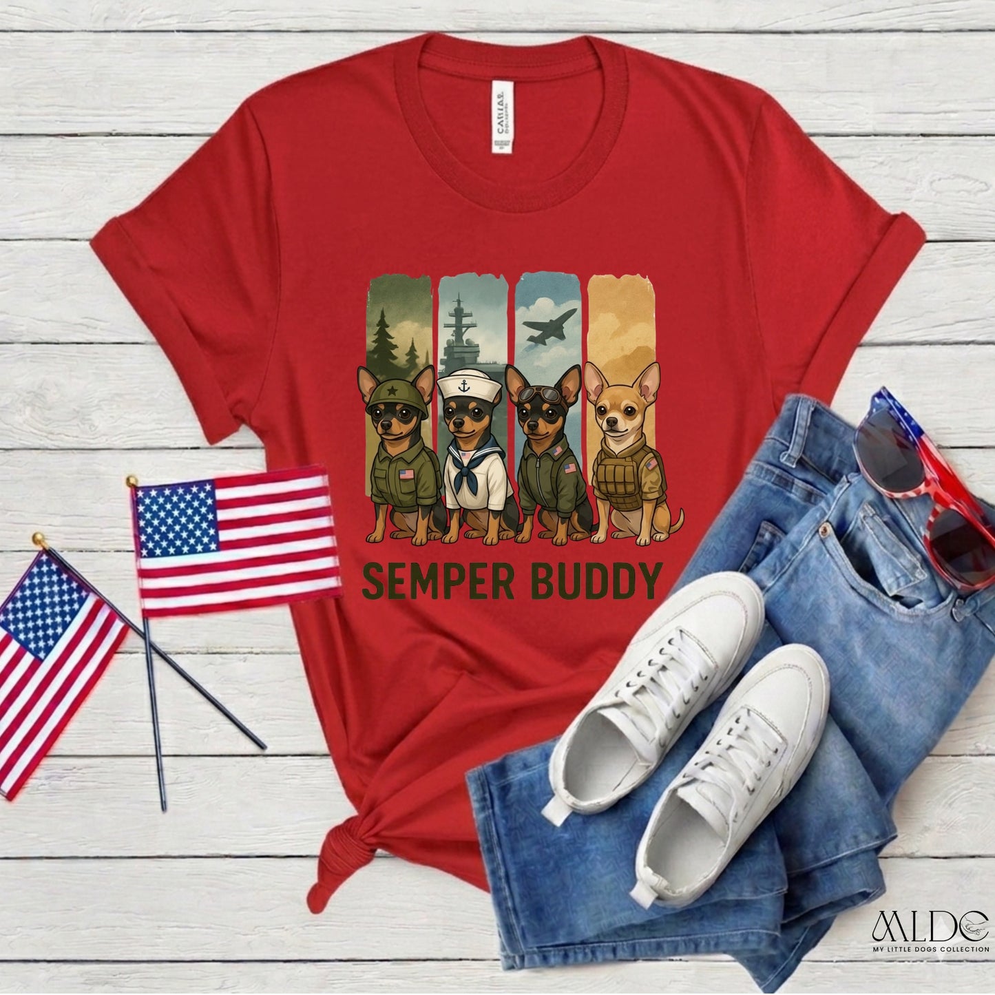 Red t-shirt with 'Semper Buddy' graphic, American flags, white sneakers, and blue jeans on a wooden surface.