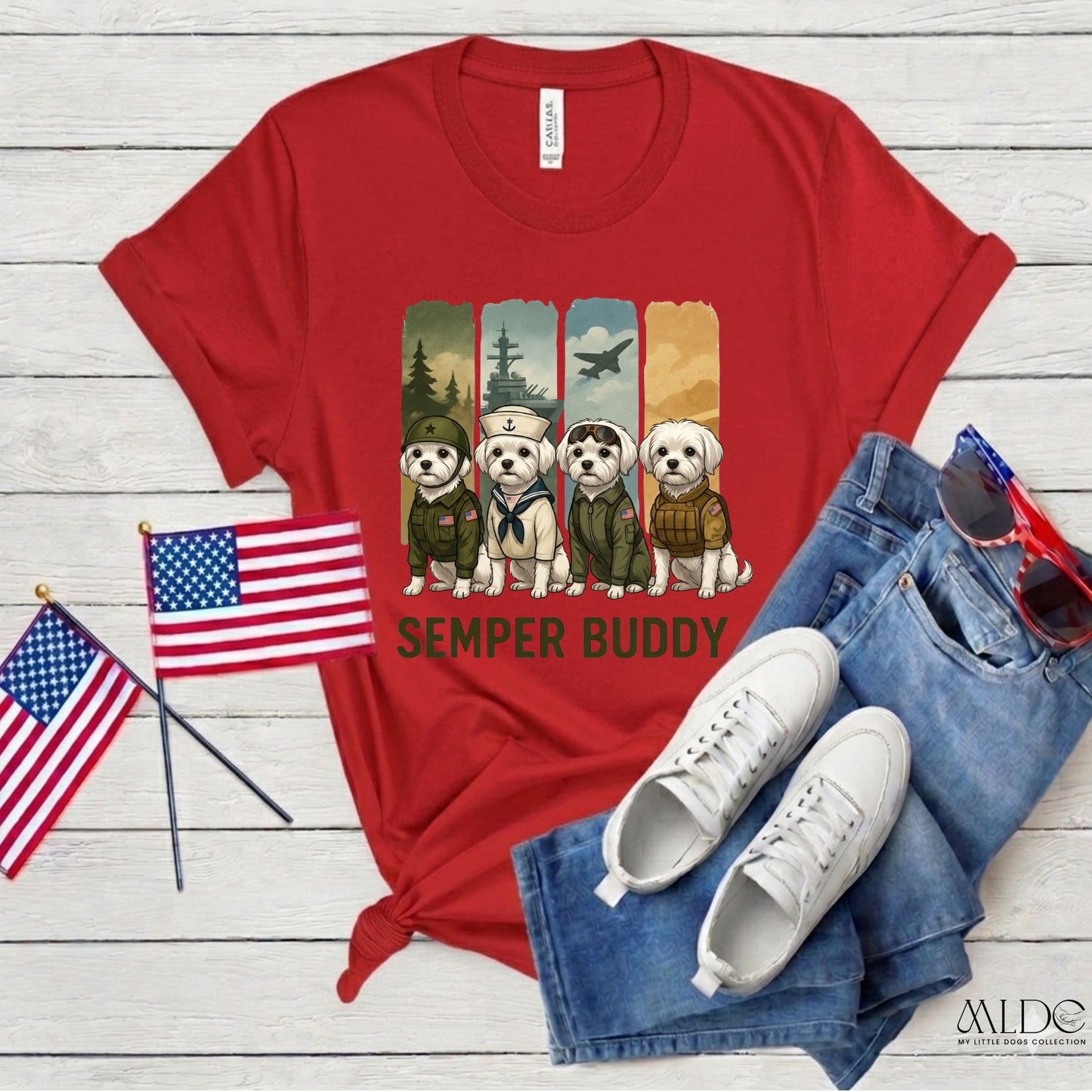 Red t-shirt with 'Semper Buddy' design, American flags, white sneakers, and blue jeans on a wooden surface.