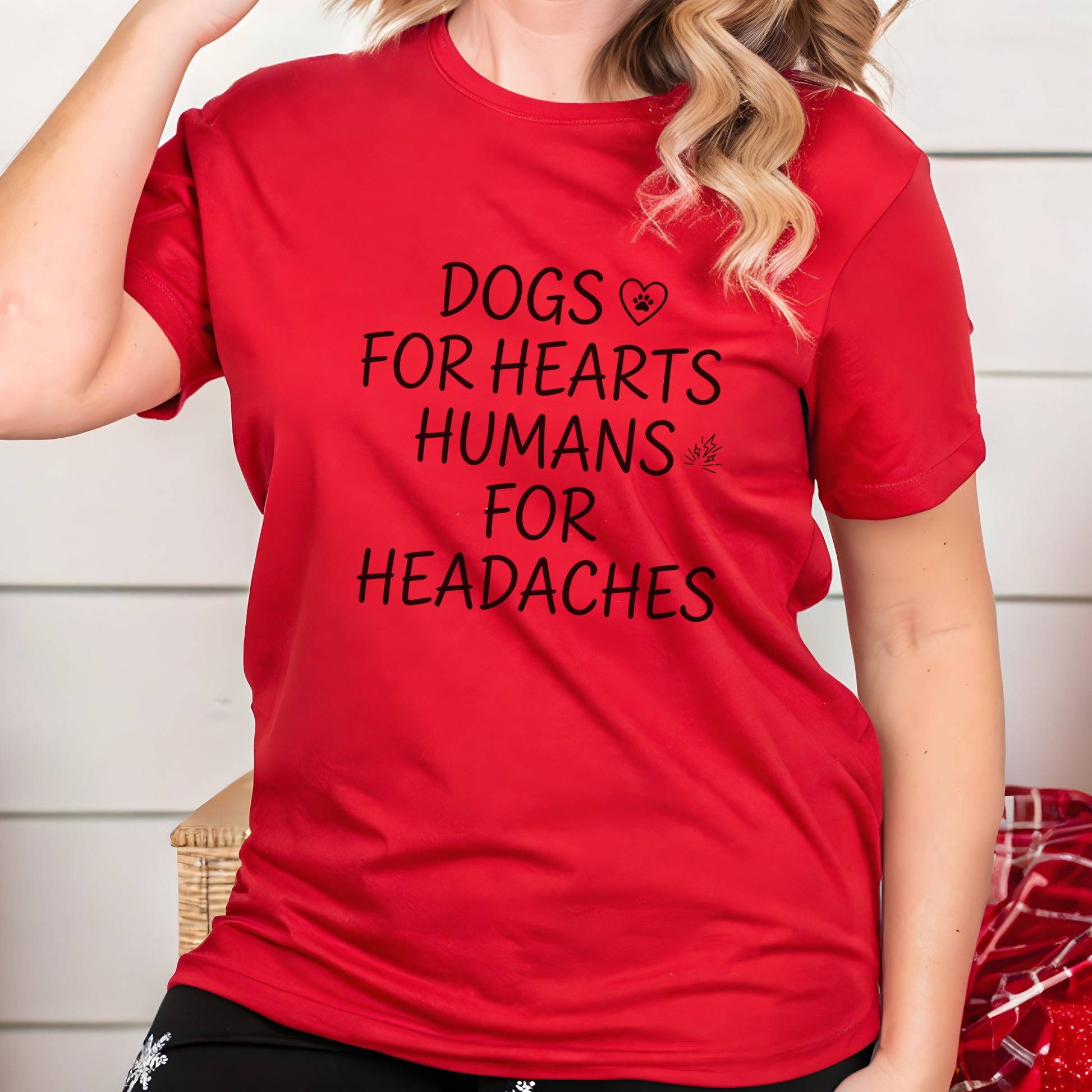 Person wearing a red t-shirt with text 'DOGS FOR HEARTS HUMANS FOR HEADACHES' against a neutral background