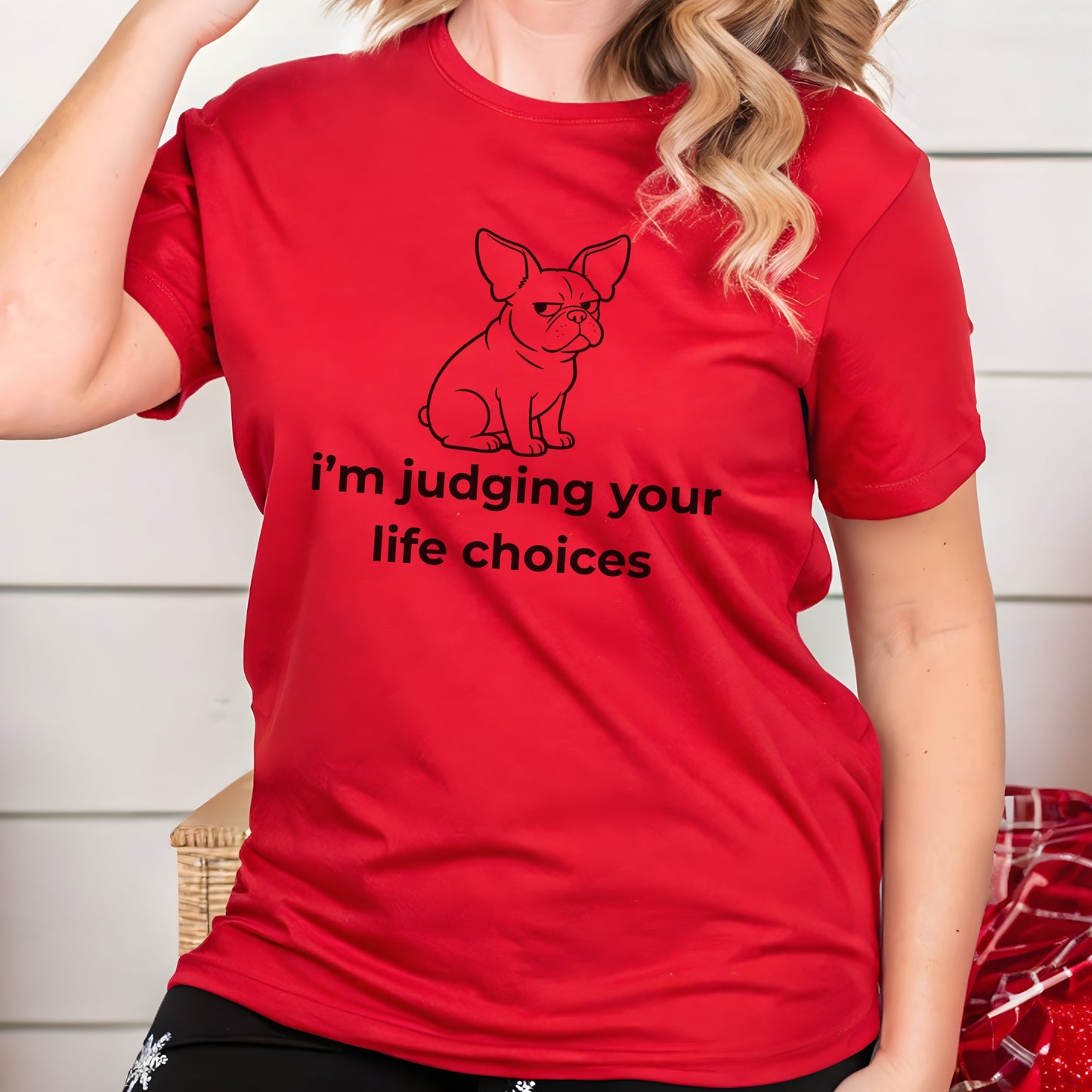 Person wearing a red t-shirt with a graphic of a dog and text, standing against a light-colored wall.