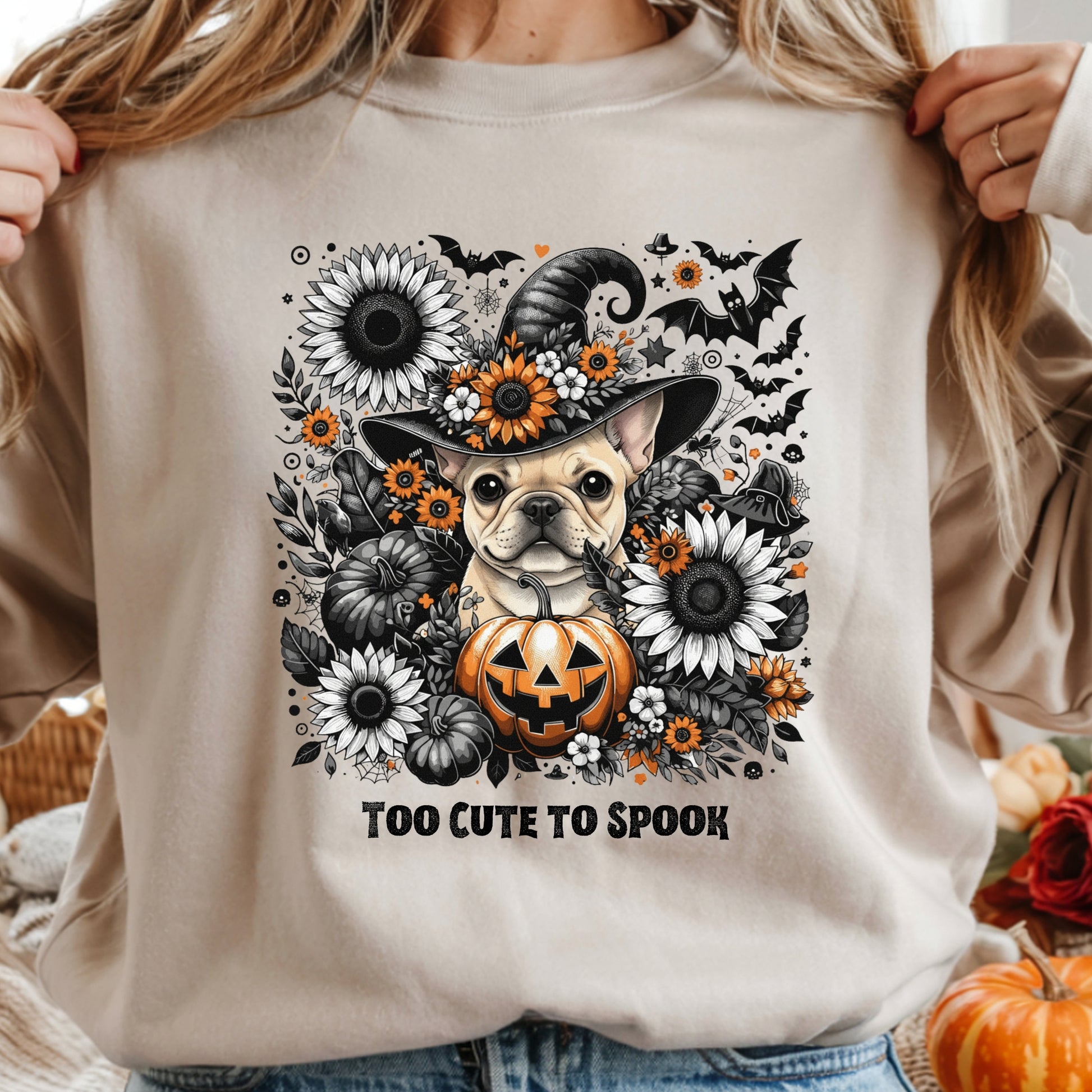 Beige sweatshirt with a Halloween-themed design featuring a dog in a witch hat, pumpkins, and flowers.