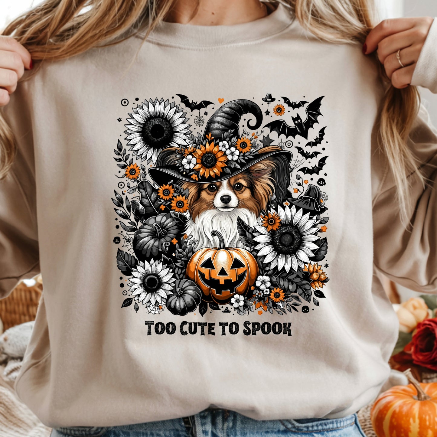 Beige sweatshirt with a Halloween-themed design featuring a dog in a witch hat, pumpkins, and flowers.