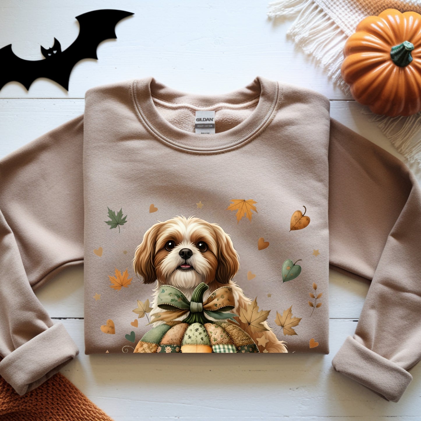 Folded sweatshirt with a dog and autumn design on a wooden surface with Halloween decorations.