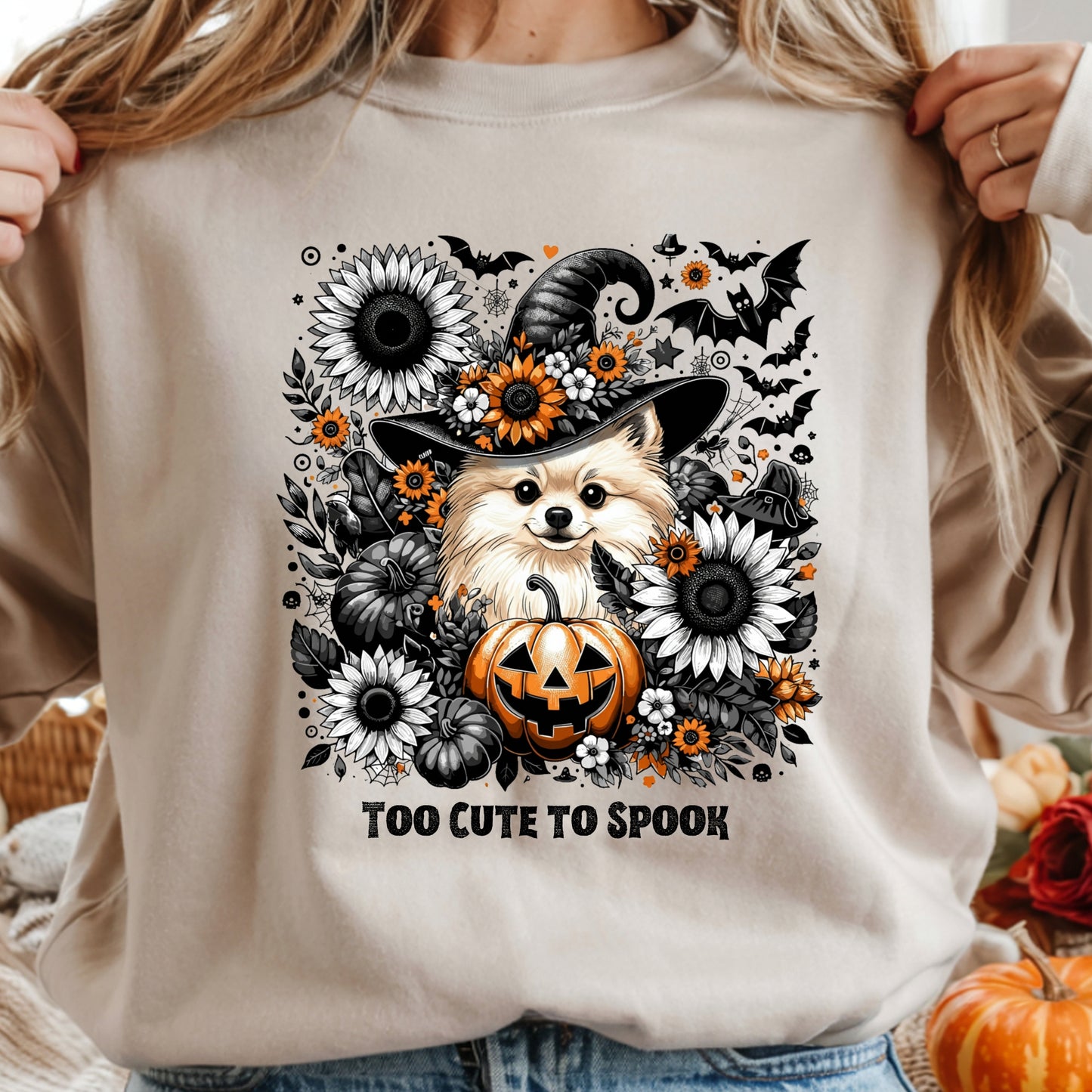 Beige sweatshirt with Halloween-themed design featuring a dog in a witch hat, pumpkins, and flowers.
