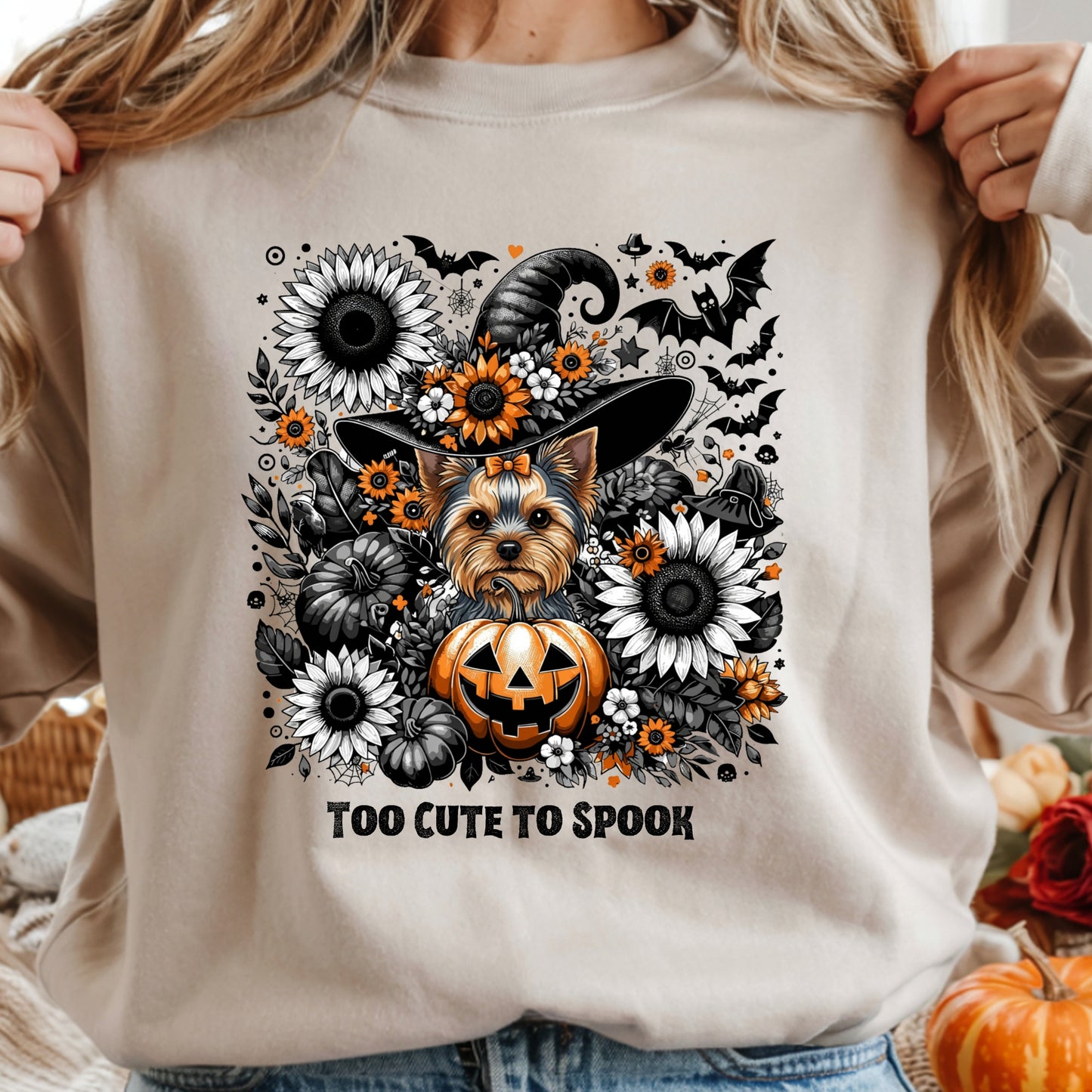 Beige sweatshirt with a dog in a witch hat surrounded by Halloween elements and 'Too Cute To Spook' text.