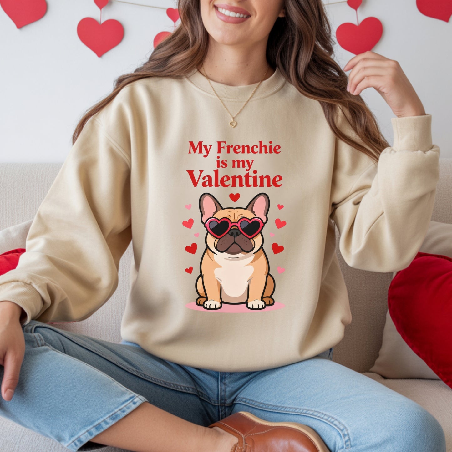 Person wearing a beige sweatshirt with a dog graphic and text, sitting on a couch with heart decorations.