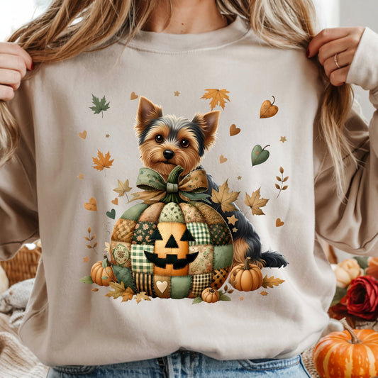 Person wearing a white sweatshirt with a dog in a pumpkin design and autumn leaves.