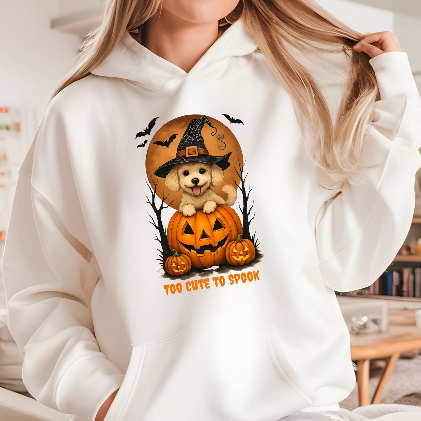 Person wearing a white hoodie with a Halloween-themed design featuring a dog in a pumpkin.