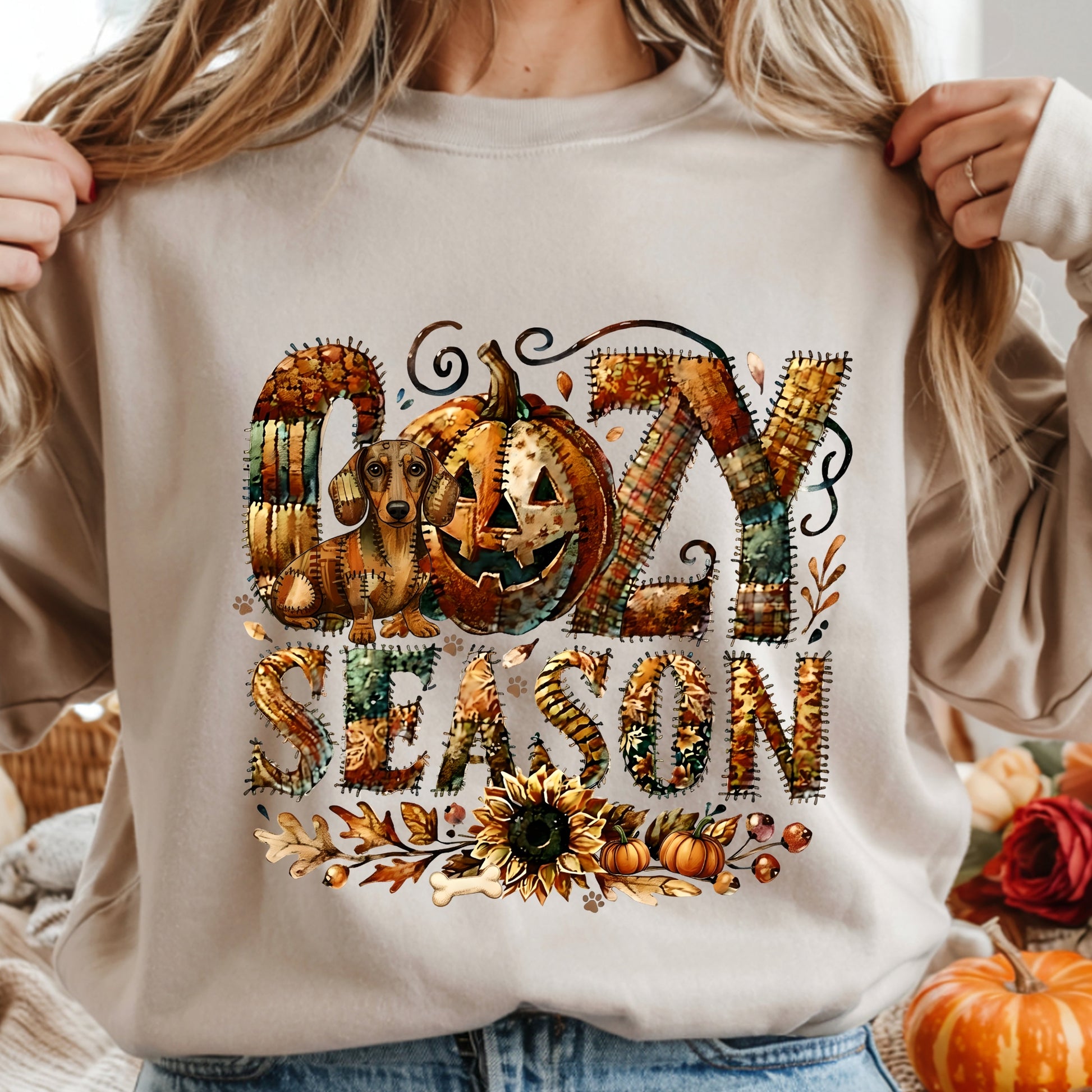 Cozy Season patchwork sweatshirt featuring a hidden Dachshound in autumn colors, surrounded by pumpkins, leaves, and a sunflower.Cozy patchwork sweatshirt with "Cozy Season" text, autumn colors, pumpkins, sunflower, and a hidden Dachshound motif.