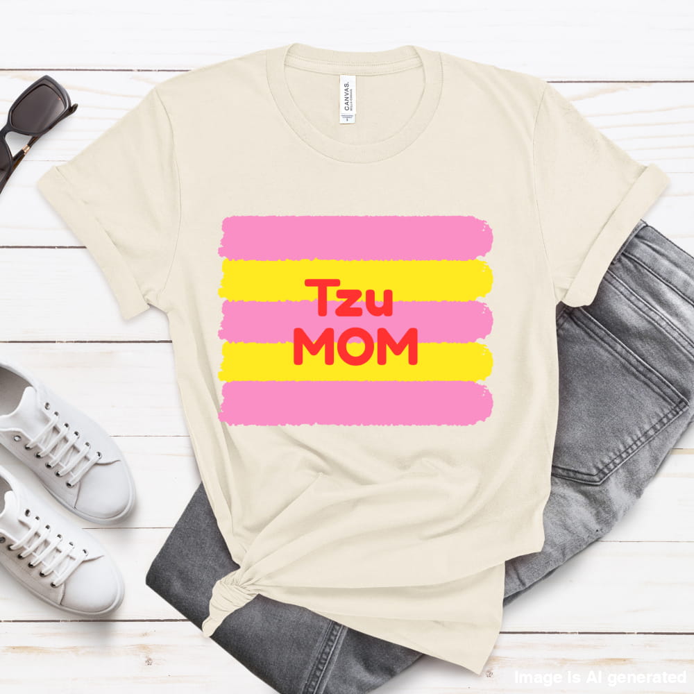 Beige t-shirt with 'Tzu MOM' text on a wooden surface with shoes and jeans.