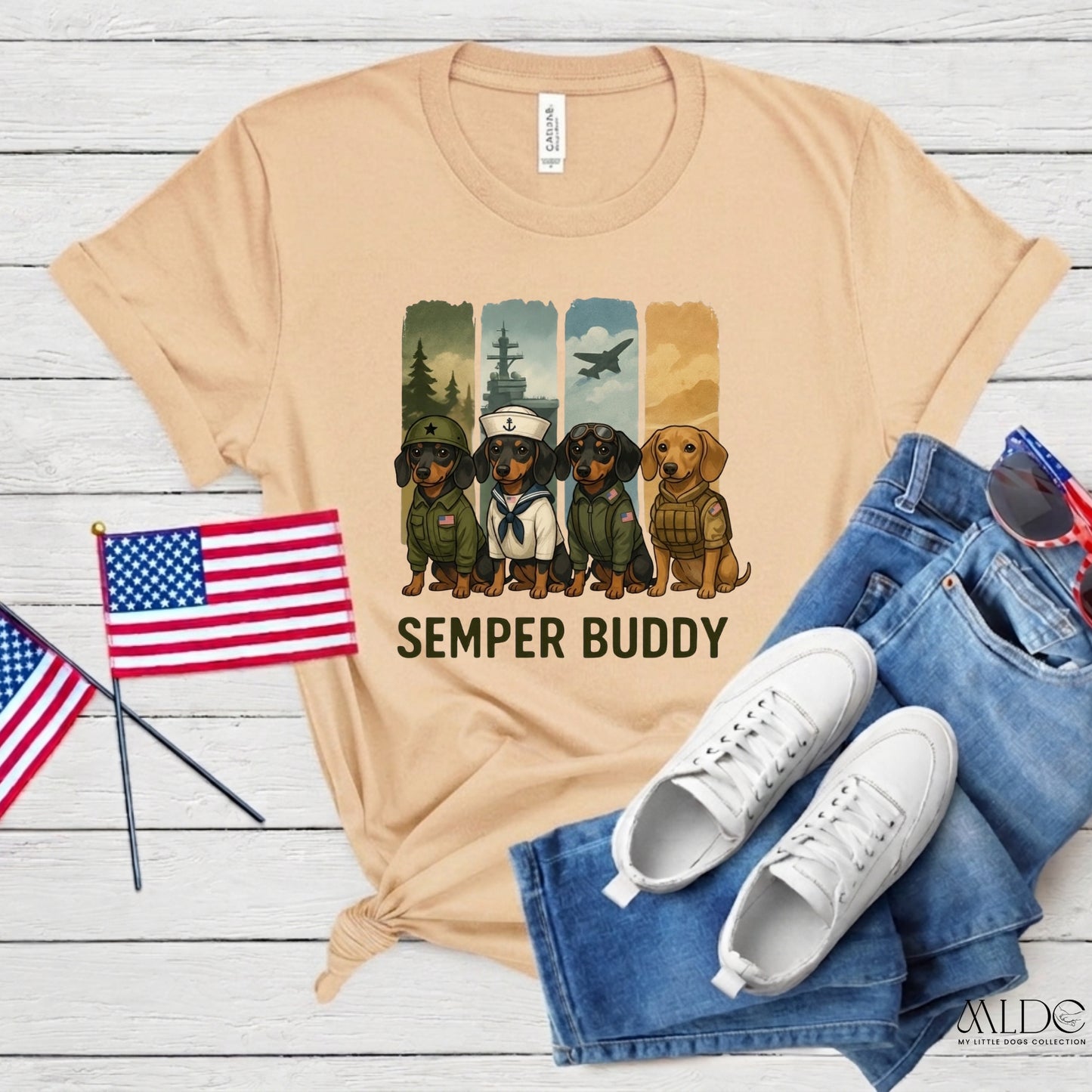 Beige t-shirt with 'Semper Buddy' graphic, American flags, white sneakers, and blue jeans on a wooden surface.