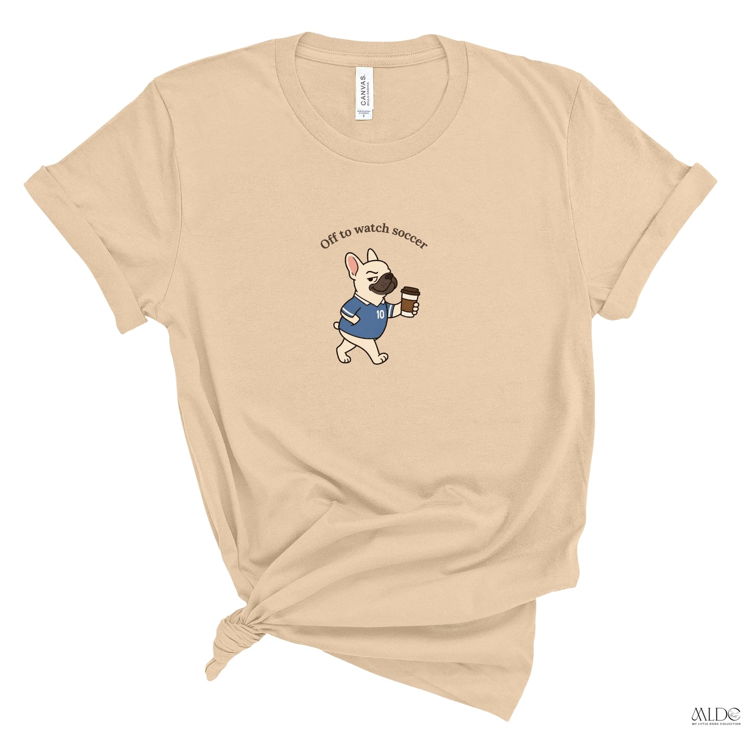 Beige t-shirt with a dog graphic and text 'Off to watch soccer' on a white background
