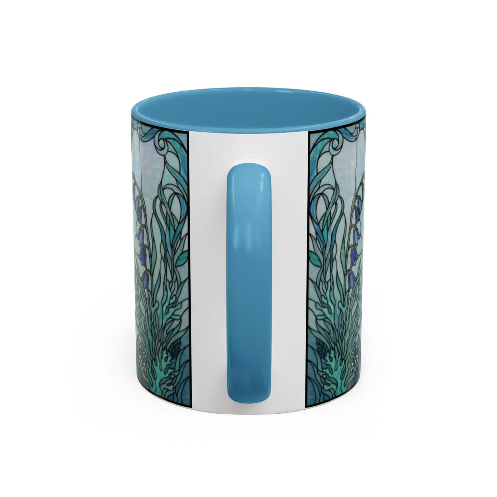 A ceramic mug with a light blue interior and handle, featuring a white center band and a detailed teal and blue botanical pattern on the sides, shown against a plain white background.