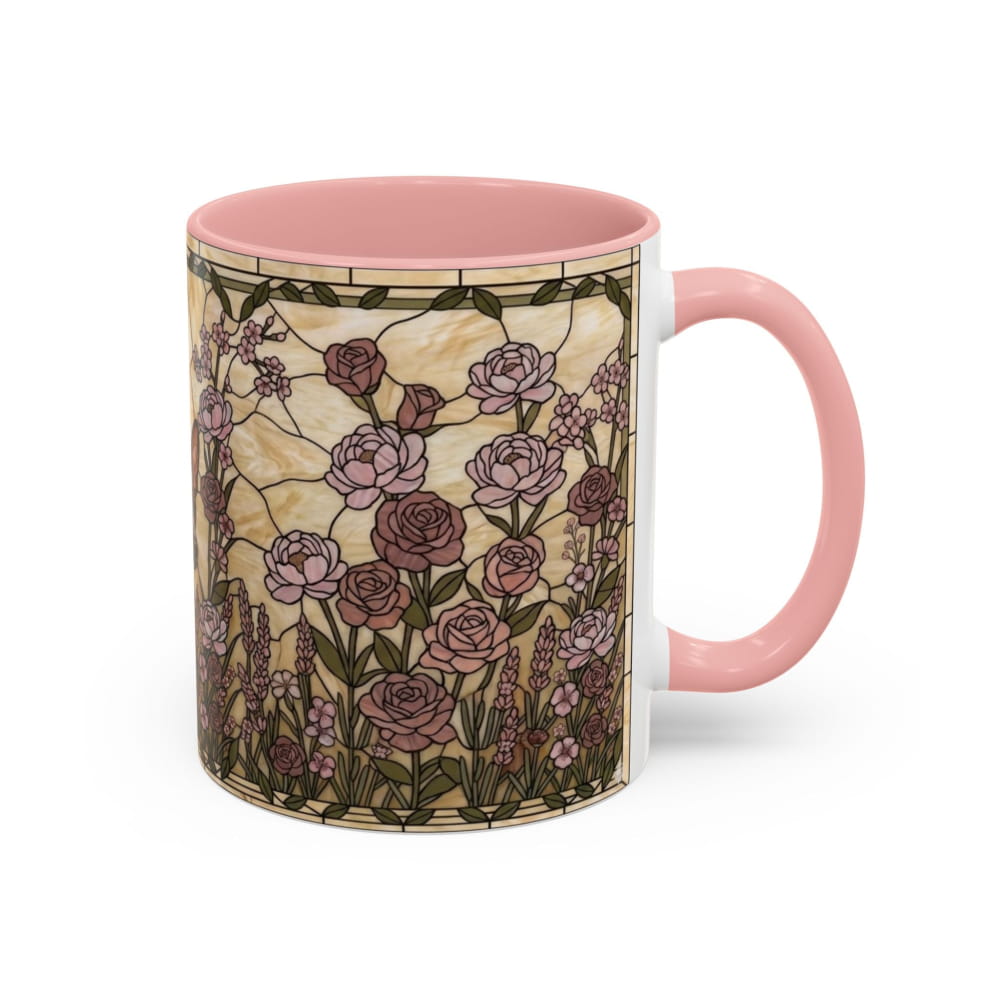 A ceramic mug with a pink handle and interior, featuring a vintage stained-glass style floral pattern with pink and mauve roses on a beige background.