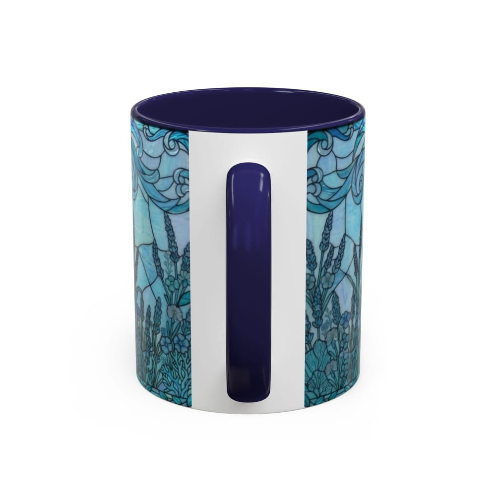 A ceramic mug with a white body, a dark blue handle and interior, and a blue and teal stained-glass style floral pattern on the exterior, shown on a white background.