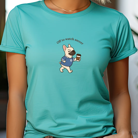 Person wearing a teal t-shirt with a dog graphic and text 'Off to watch soccer'.