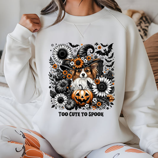 Person wearing a white sweatshirt with a Halloween-themed design featuring a dog, pumpkins, and flowers.