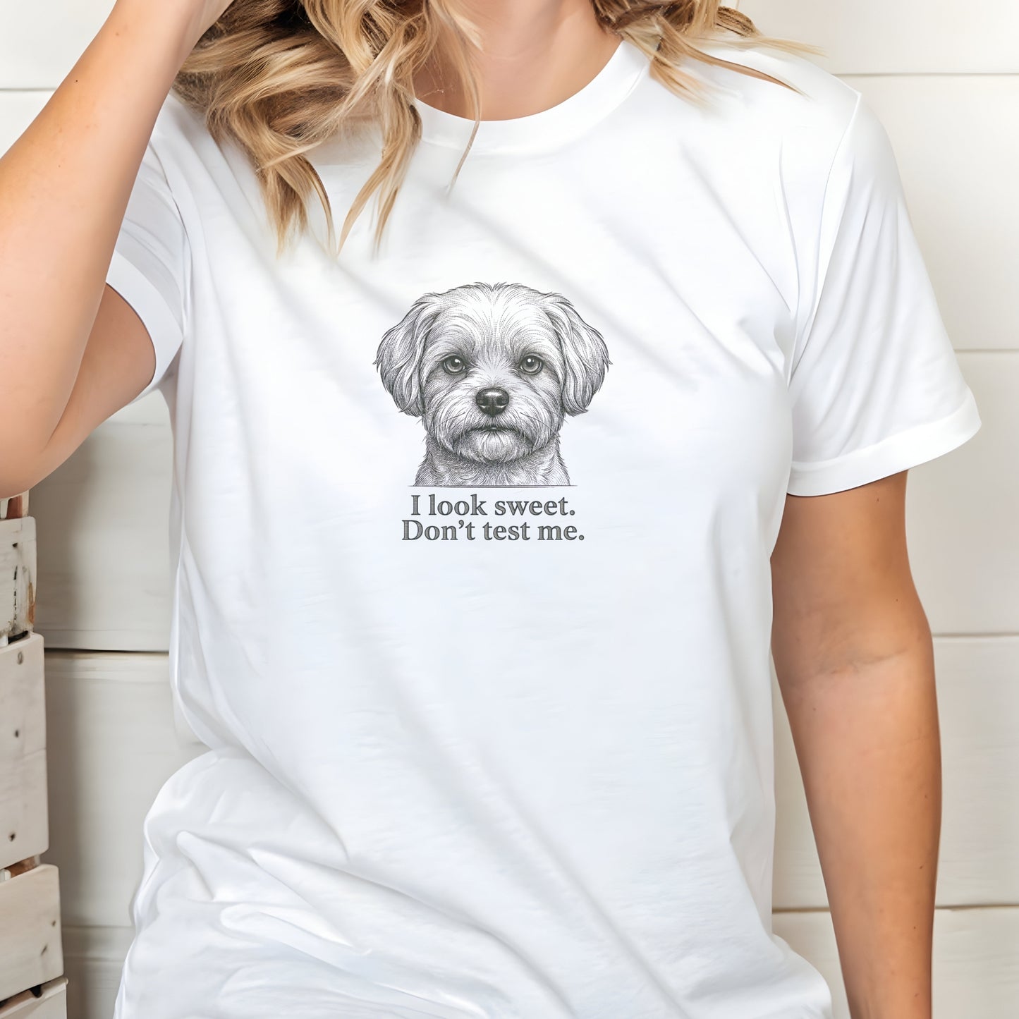 White t-shirt with a dog graphic and text worn by a person indoors.
