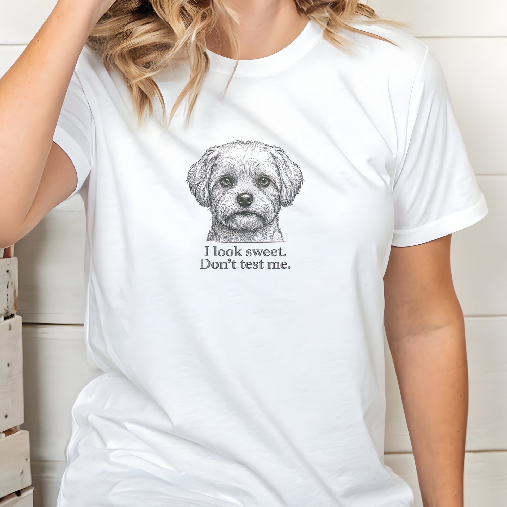 White t-shirt with a dog graphic and text worn by a person indoors.