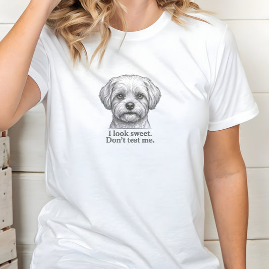 White t-shirt with a dog graphic and text worn by a person indoors.