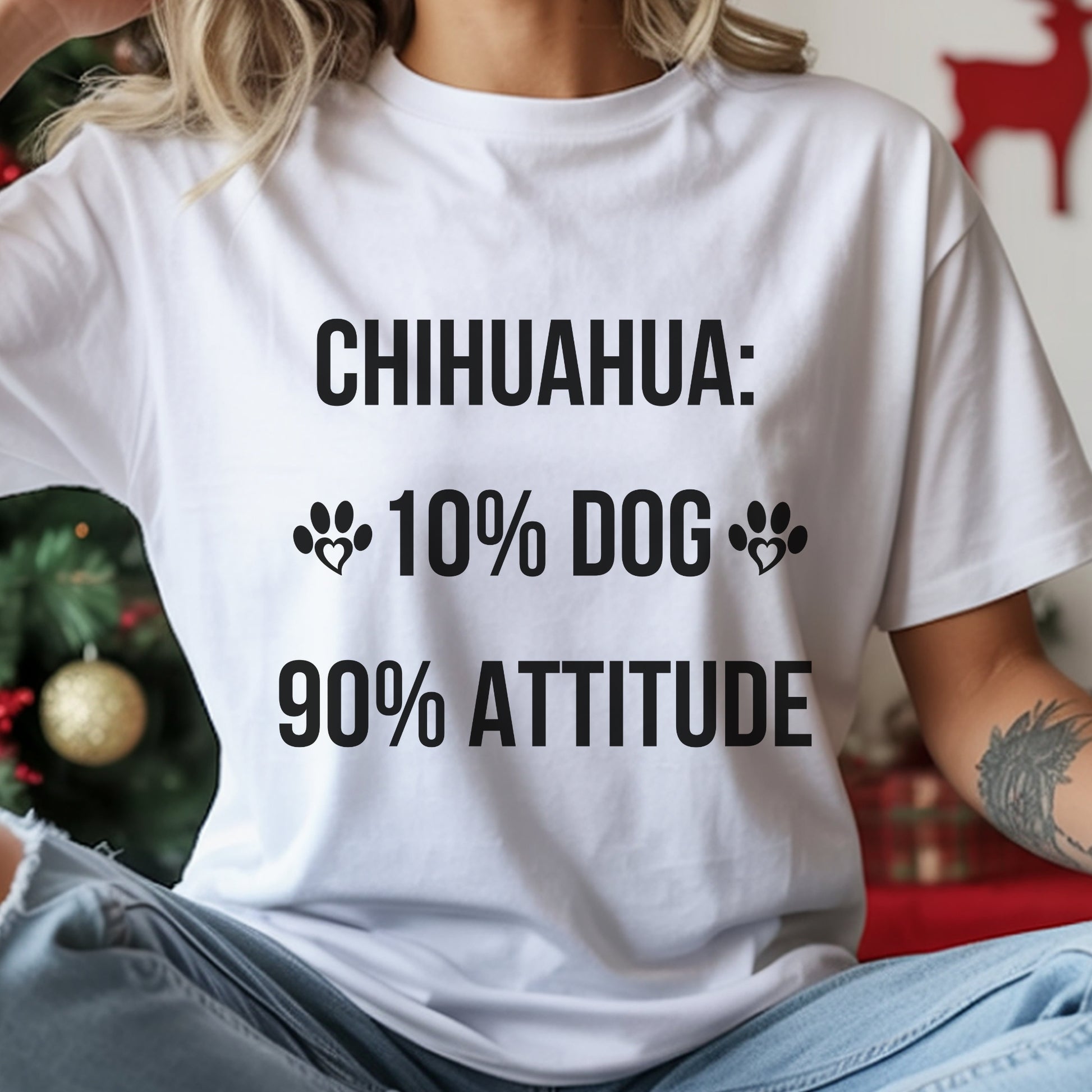 Person wearing a white t-shirt with text about Chihuahuas in front of a Christmas tree.