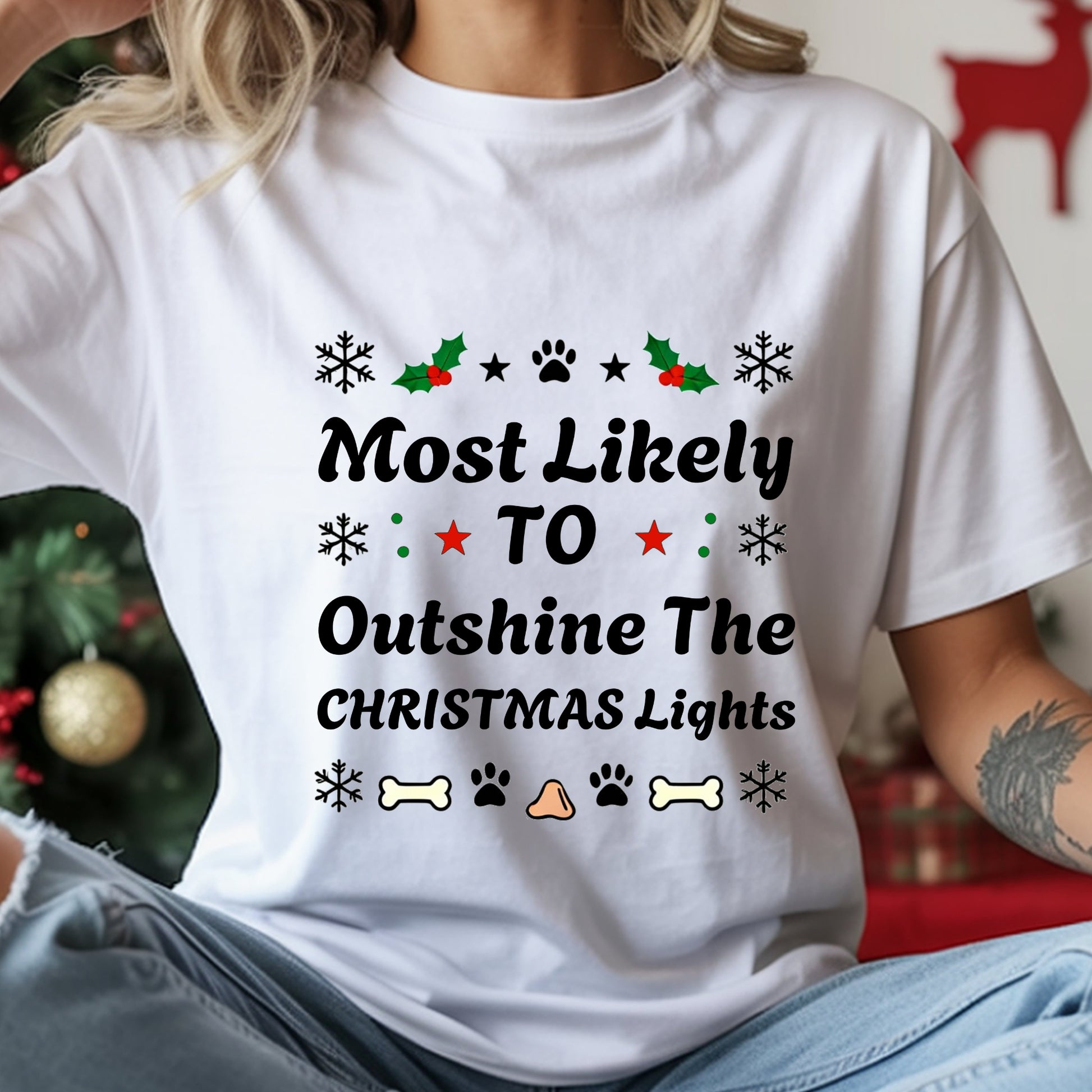 White t-shirt with Christmas-themed text and graphics worn by a person, with a festive background.