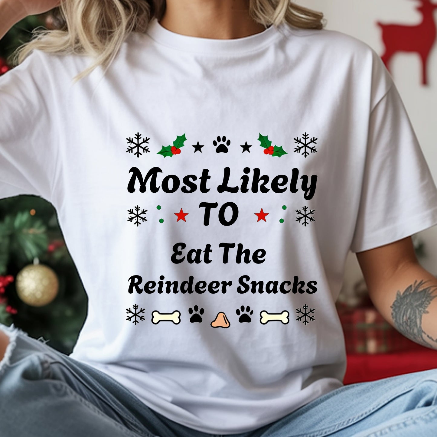 White t-shirt with Christmas-themed text and graphics worn by a person, with a festive background.