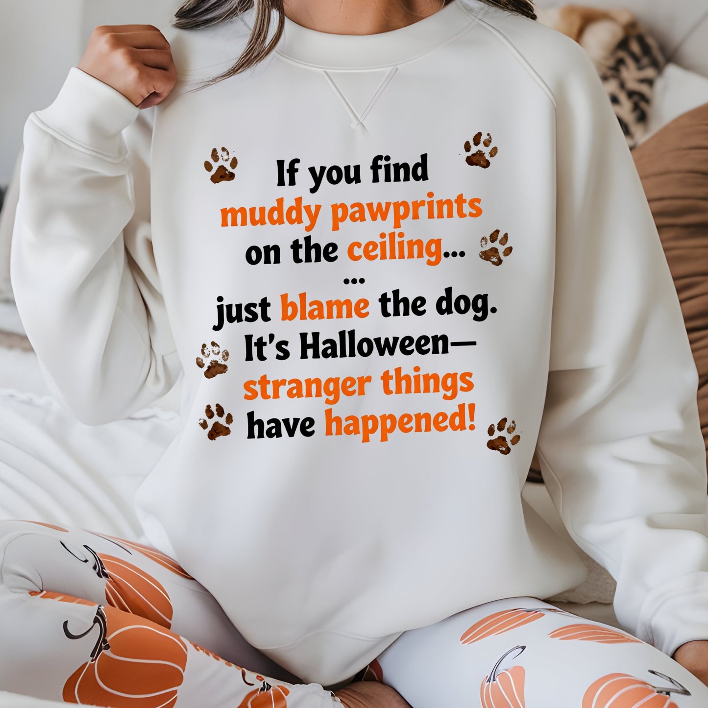 Person wearing a white sweatshirt with Halloween-themed text and paw prints.