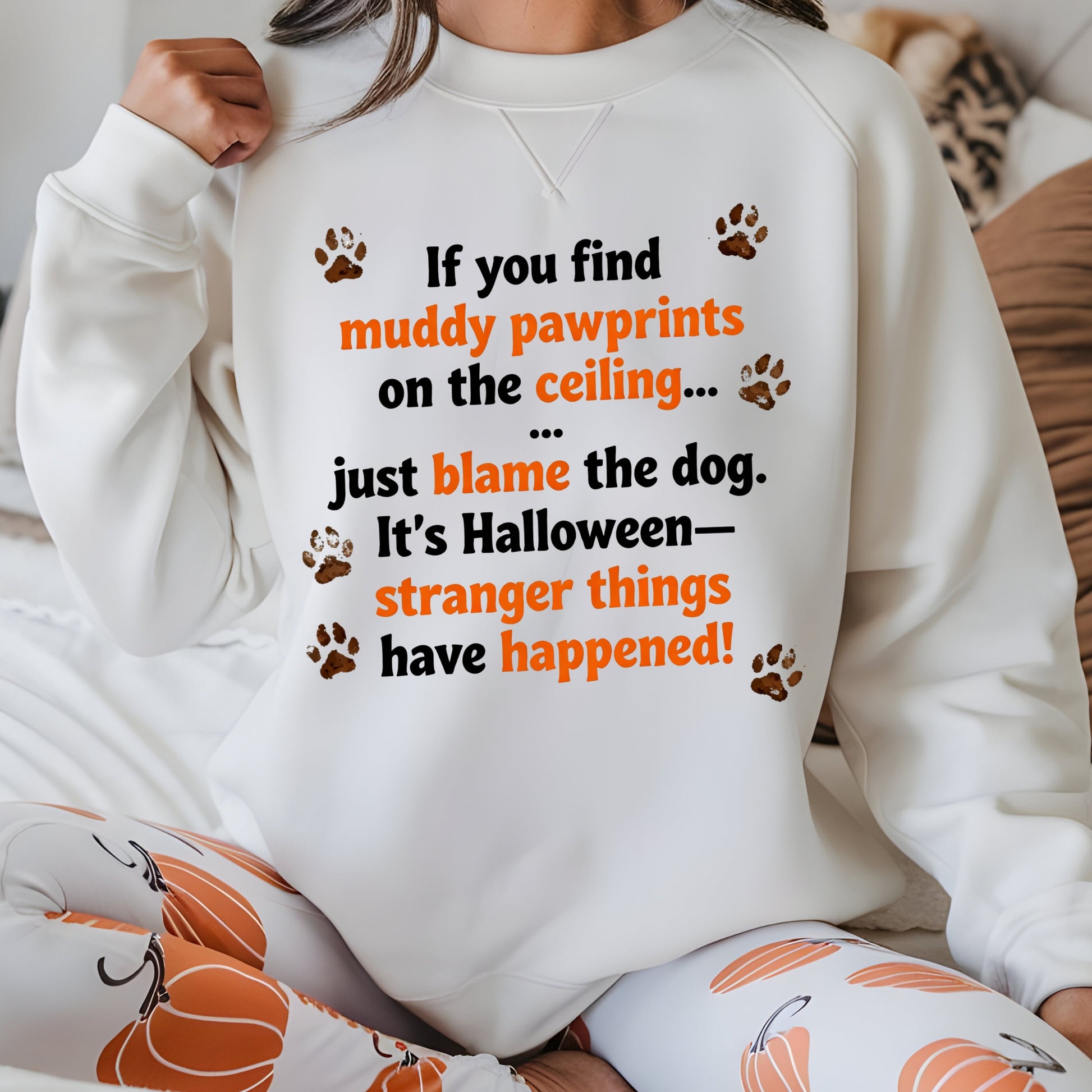 Person wearing a white sweatshirt with Halloween-themed text and paw prints.
