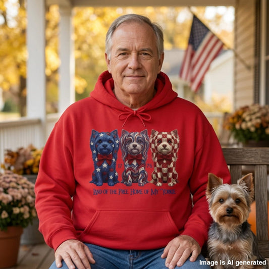 Man in a red Land of the Free hoodie with three patriotic Yorkies, sitting on a porch next to his Yorkie under an American flag